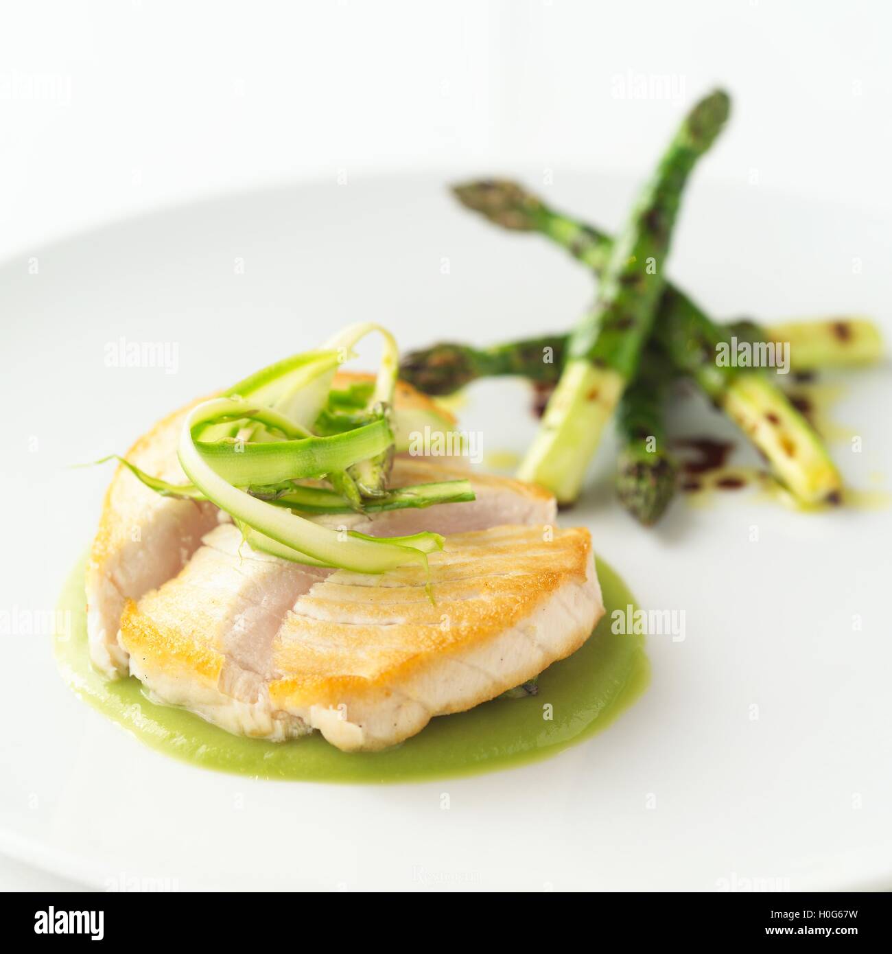 Swordfish with asparagus and green chickpeas on white background Stock