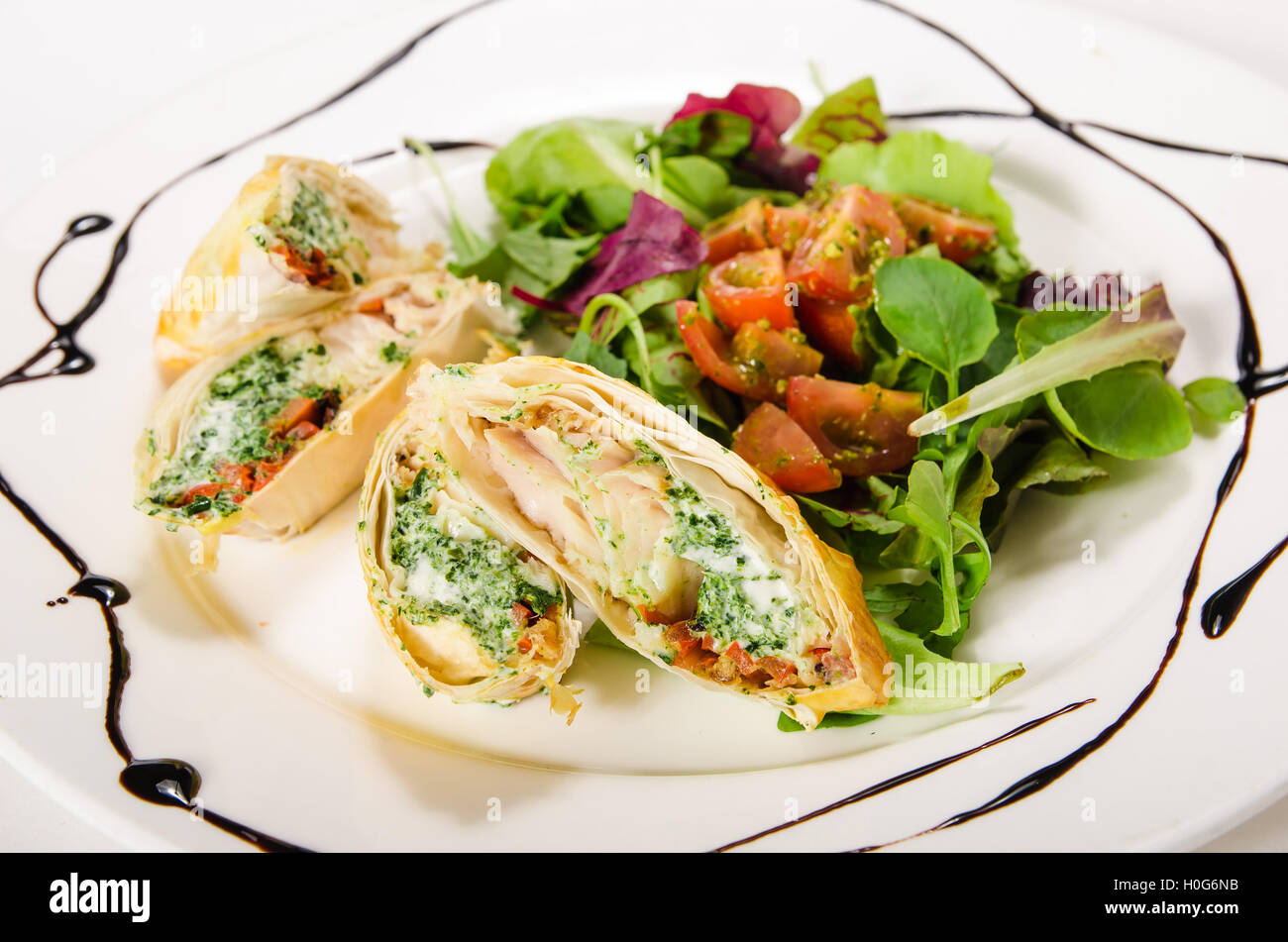 Pike perch fillet with cream cheese and spinach in phyllo dough with a light green mix Stock Photo