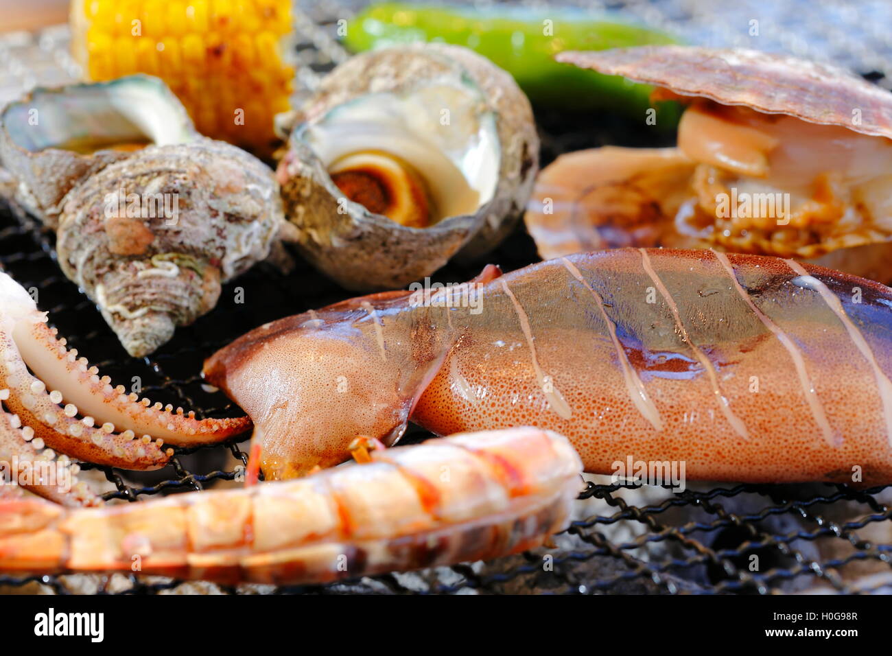 Grilling abalone, squid, shrimp, clams and corn with hot charcoal Stock Photo