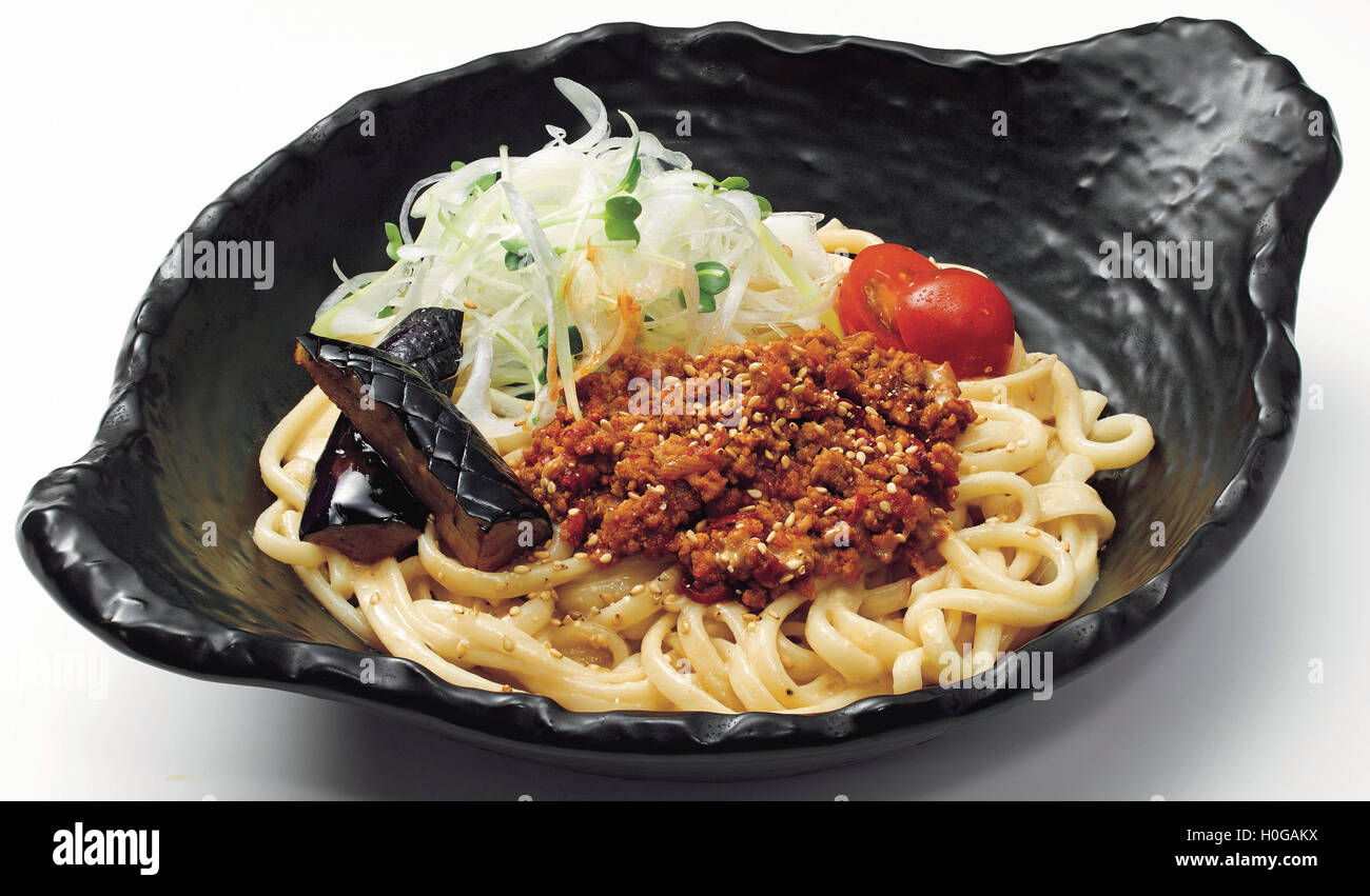 Japanese udon noodle with minced beef, onion, tomatoes and botanical egg in black bowl Stock