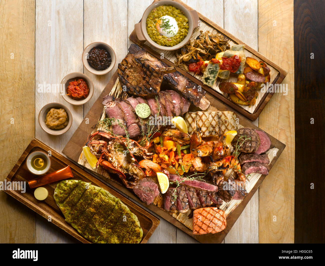 Osia Steak Seafood Grill with beef, pork, bacon, ham, sausages, lemon, herbs and wasabi on wooden table Stock Photo