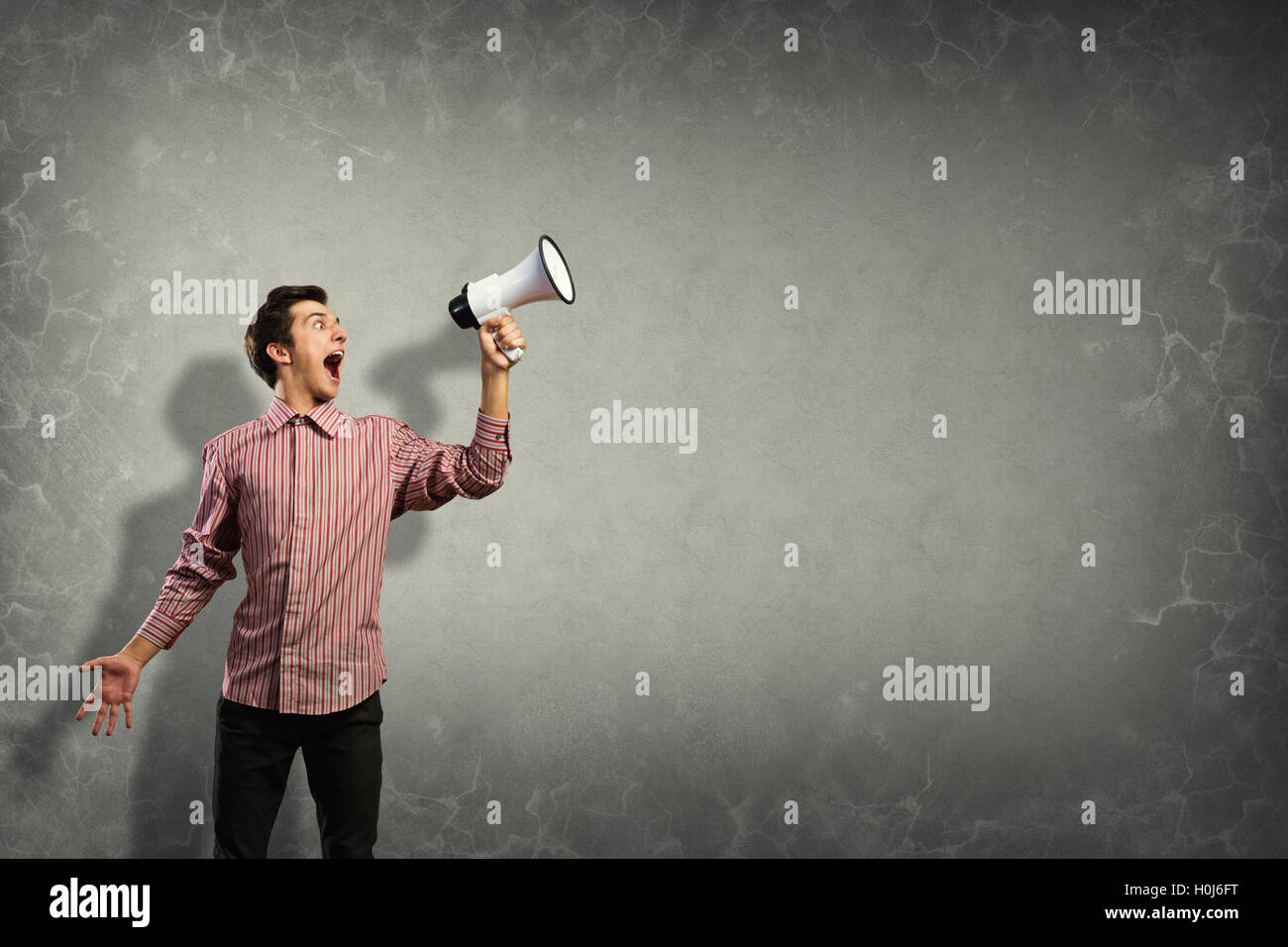 Portrait of a young man shouting using megaphone Stock Photo - Alamy