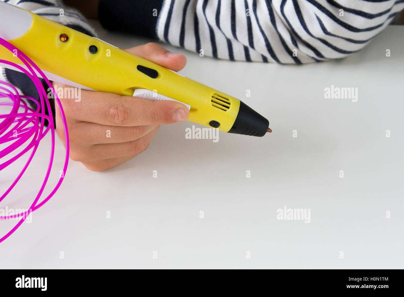 Child hands hold 3d drawing pen with filaments on white background. Top view. Copy space for text Stock Photo