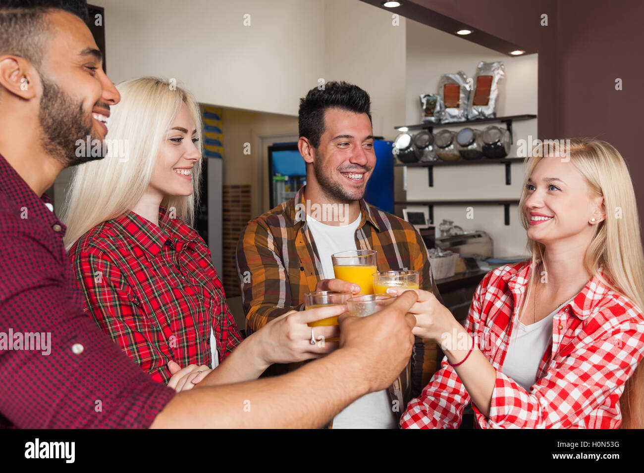 People Friends Drinking Orange Juice, Toasting At Bar Counter, Mix Race Man And Woman Cheers