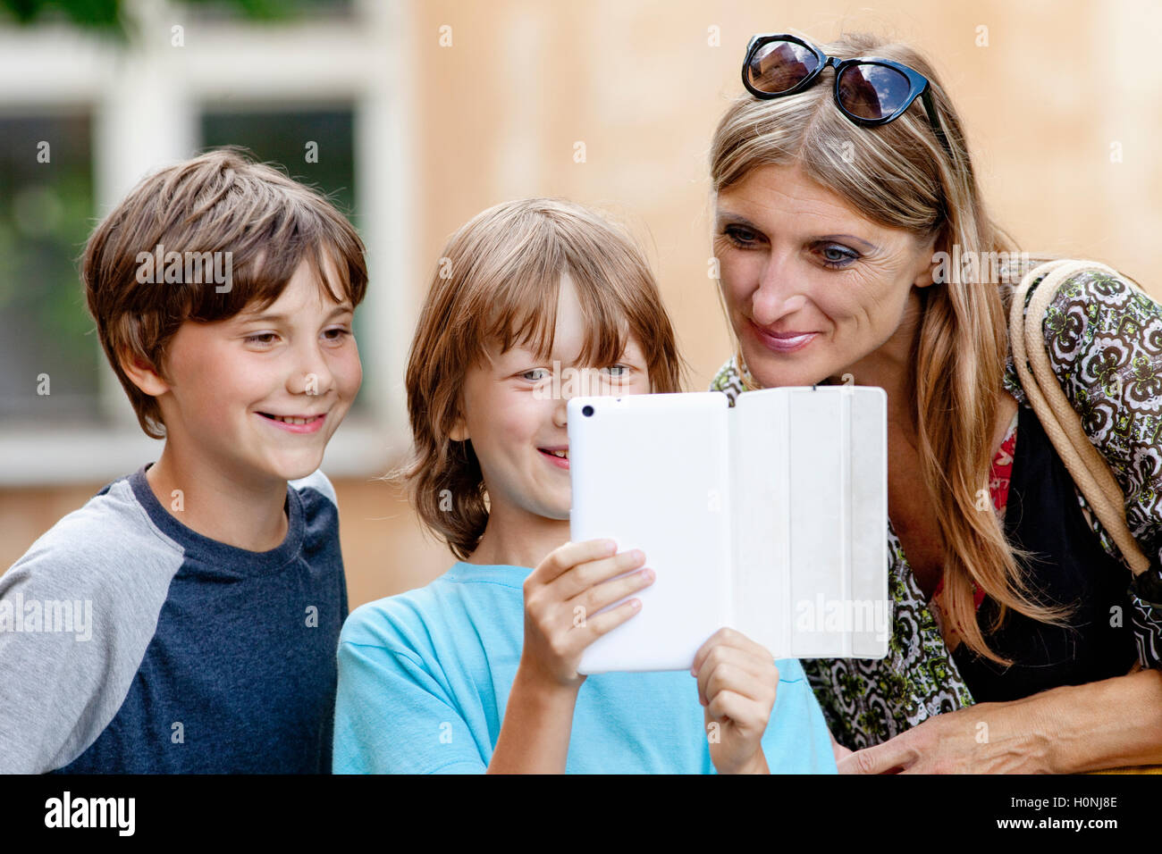 Two Boys Showing Something to Mother on Tablet Stock Photo