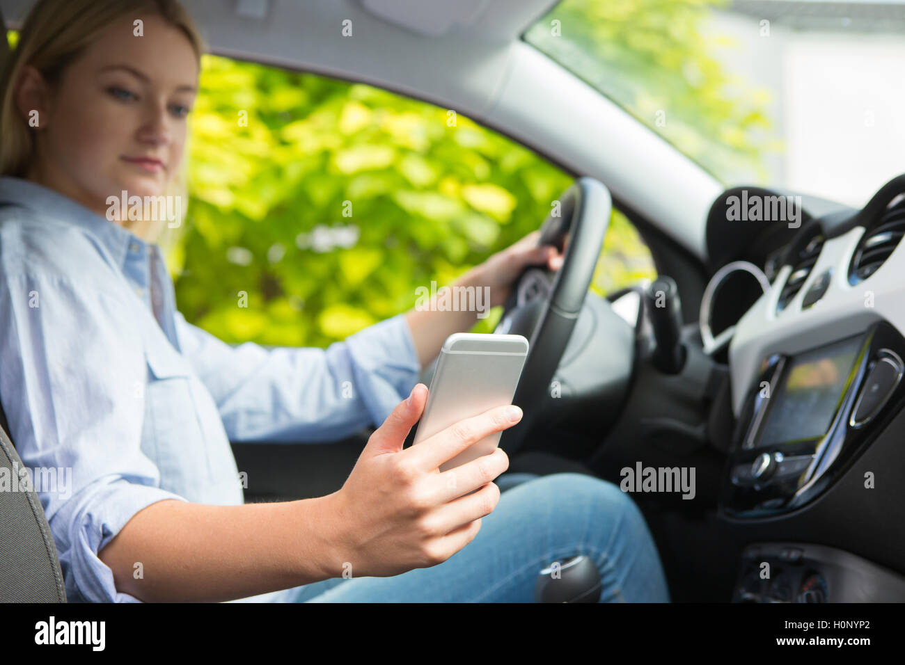 Woman In Car Texting On Mobile Phone Whilst Driving Stock Photo