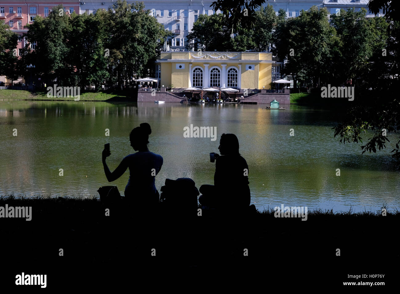A woman takes selfie photo as she sits at the bank of Patriarshiye Ponds or Patriarch's Ponds,  in Presnensky District of downtown Moscow, Russia. Stock Photo