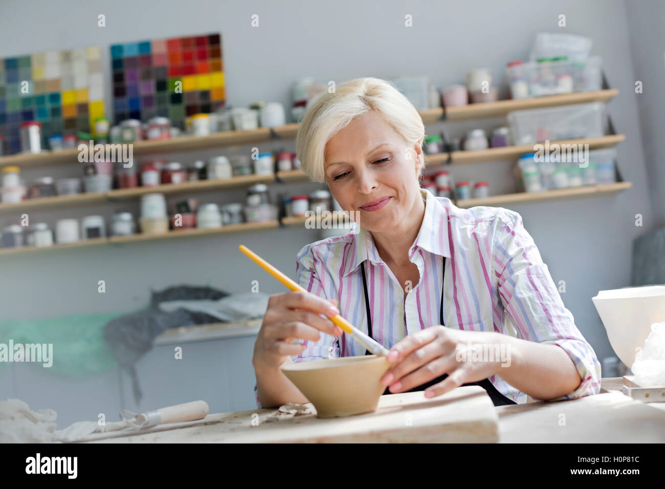 mature adult woman painting pottery bowl studio Stock Photo