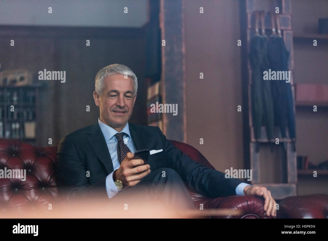 businessman texting cell phone menswear shop Stock Photo