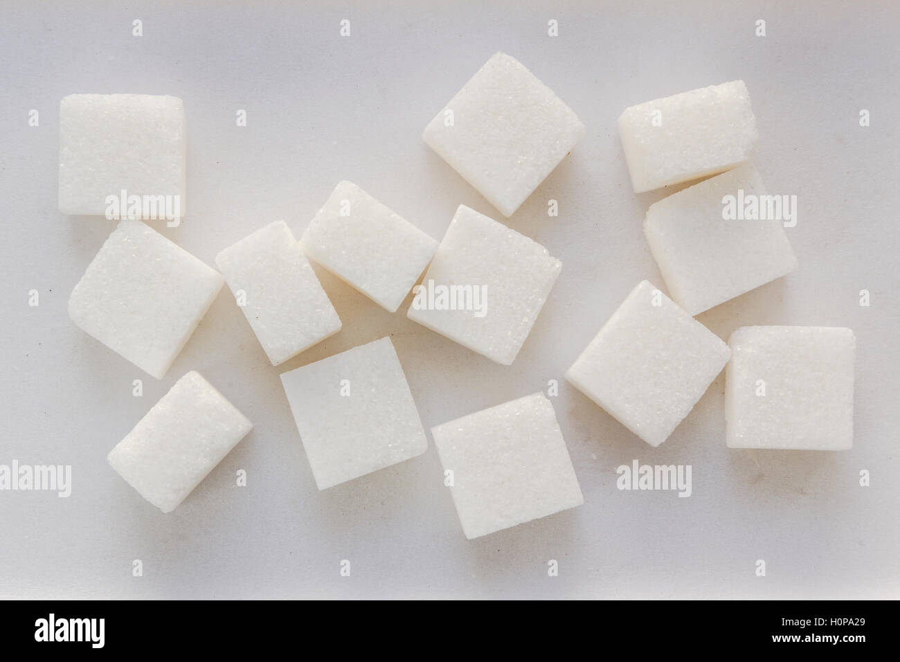 White sugar pieces on a white background. Stock Photo