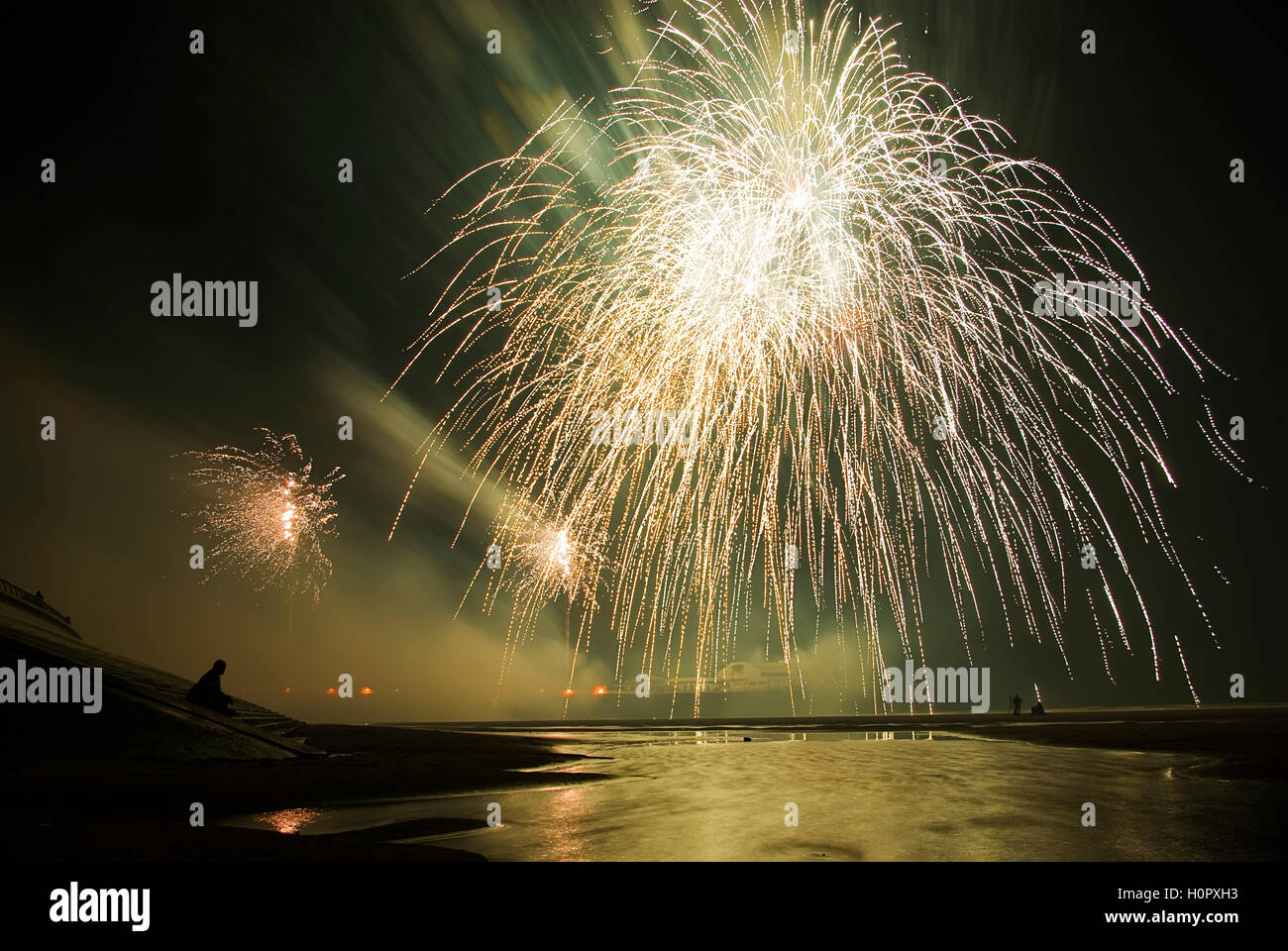 Fireworks from a pier at the seaside reflecting in the sea Stock Photo