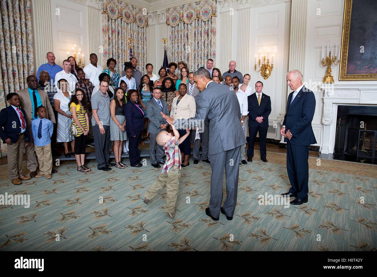 U.S. President Barack Obama high-fives a little boy as he and U.S. Vice President Joe Biden greet wounded warriors and their families during a tour of the East Room June 23, 2014 in Washington, DC. Stock Photo