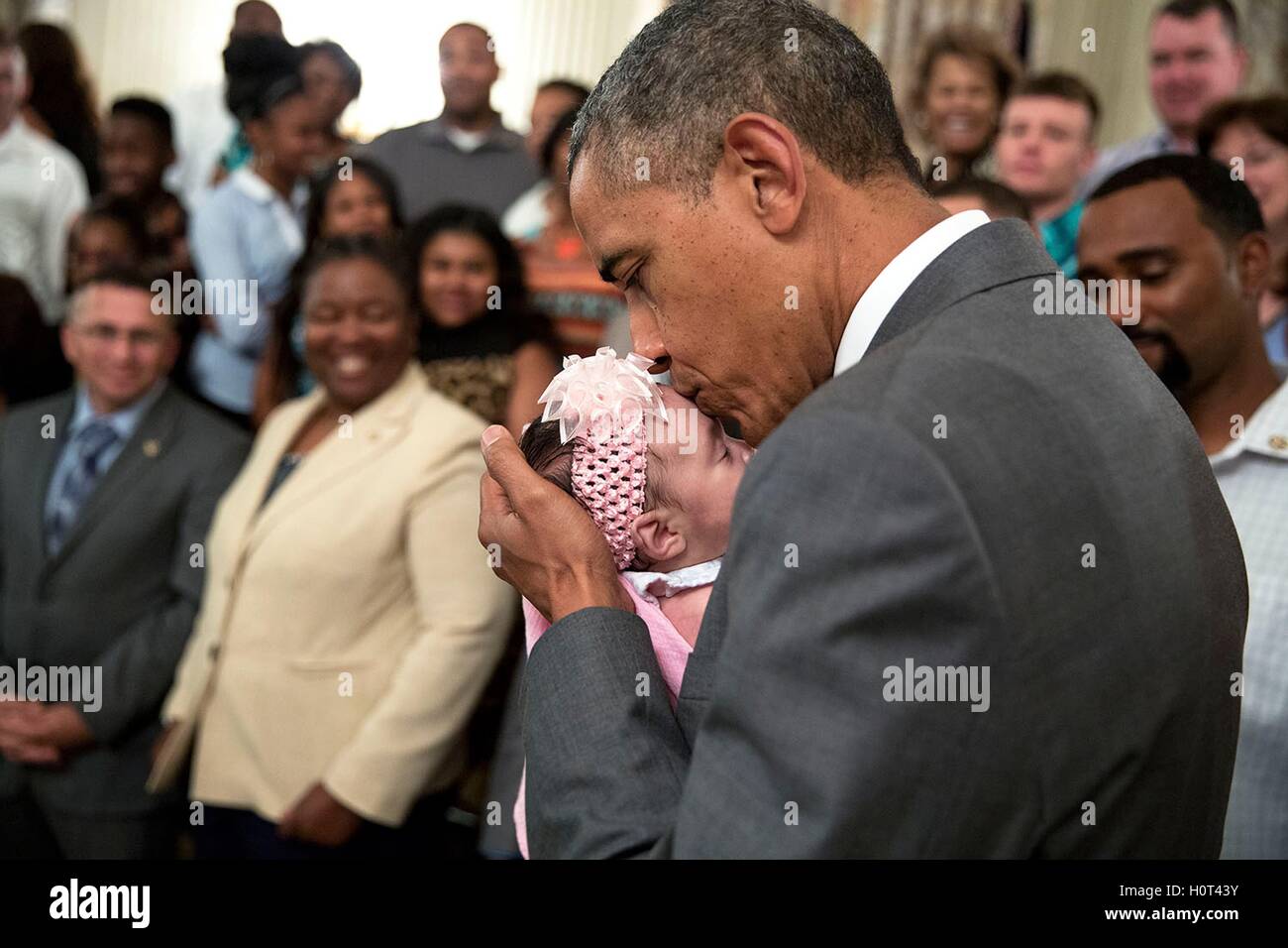 U.S. President Barack Obama kisses a baby girl as he greets wounded warriors and their families during a tour of the White House East Room June 23, 2014 in Washington, DC. Stock Photo