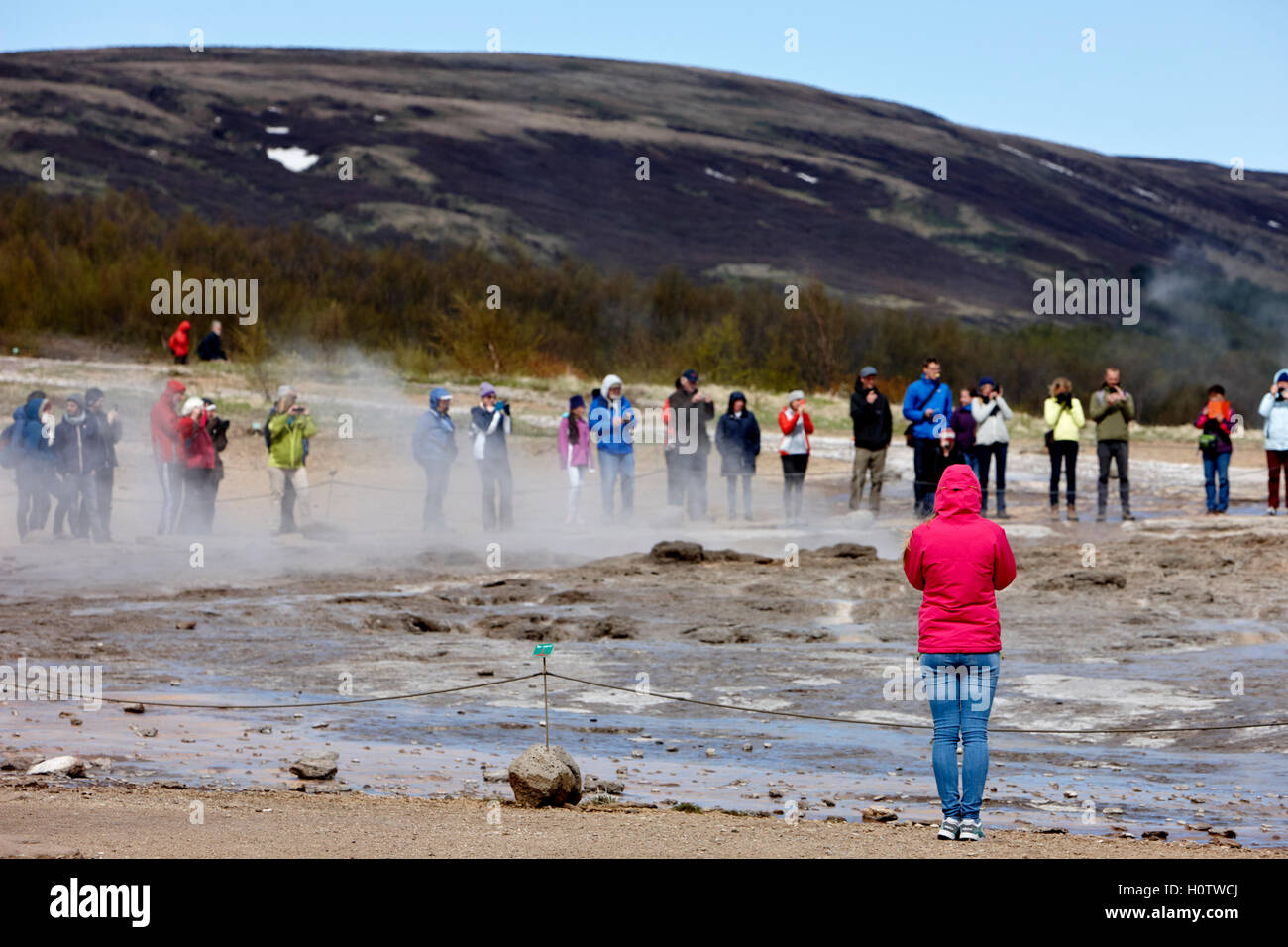tourists stand around waiting for the strokkur geyser to erupt geysir Iceland Stock Photo