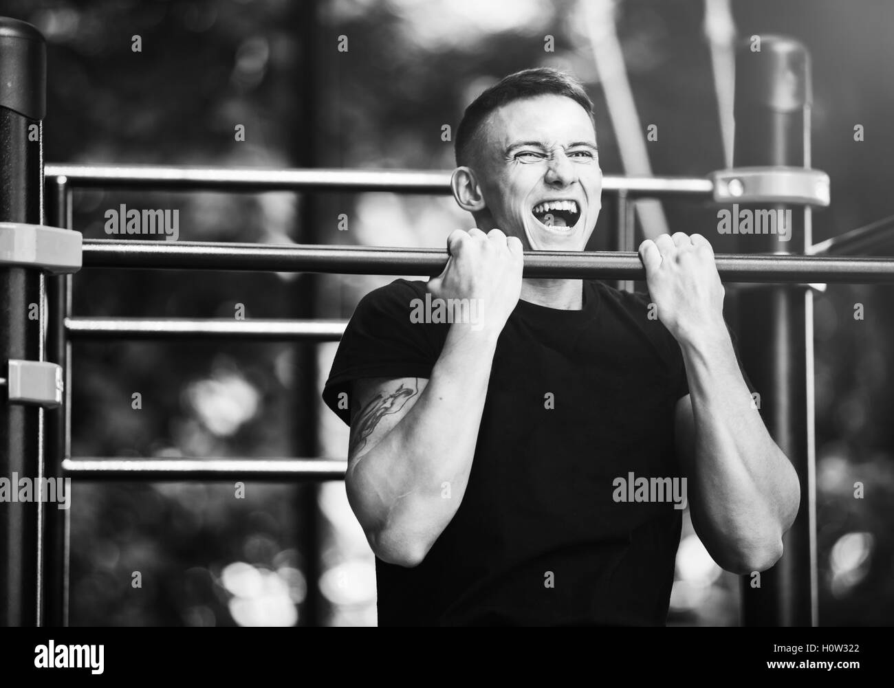 Young man doing pull ups on horizontal bar outdoors, workout, sport concept Stock Photo