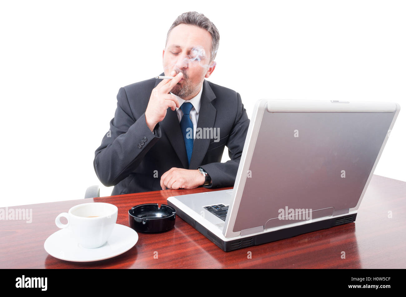 Corporate director enjoying coffee and smoking in his office isolated