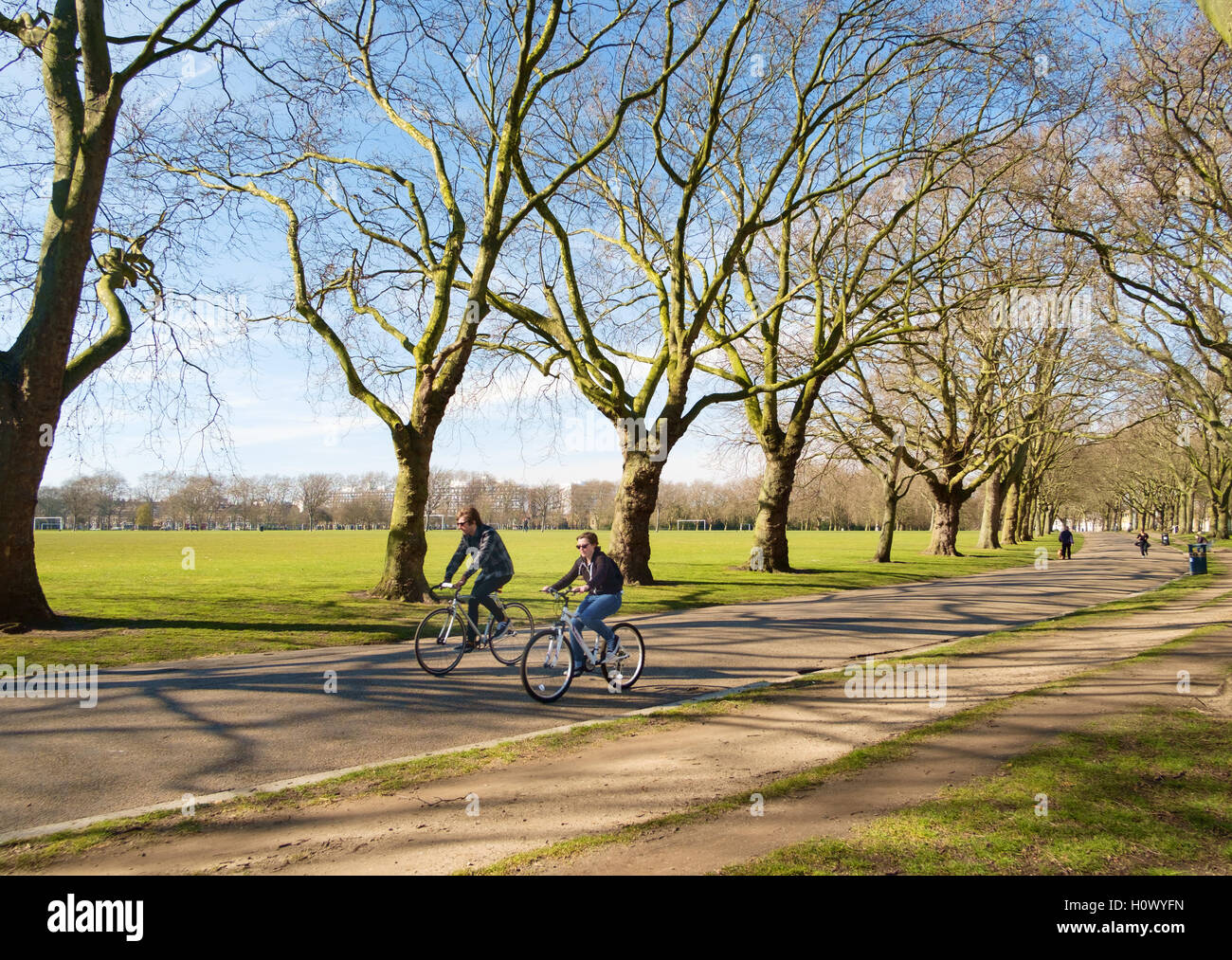 A couple cycle through Victoria Park, East London, UK Stock Photo