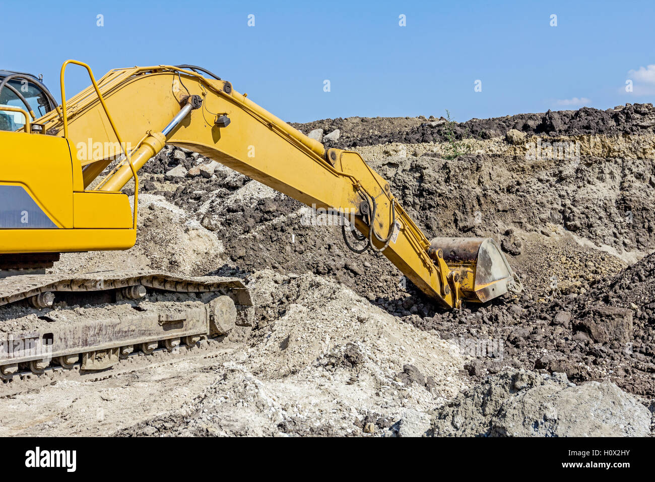 Yellow excavator is digging soil by pulling ground at construction site ...