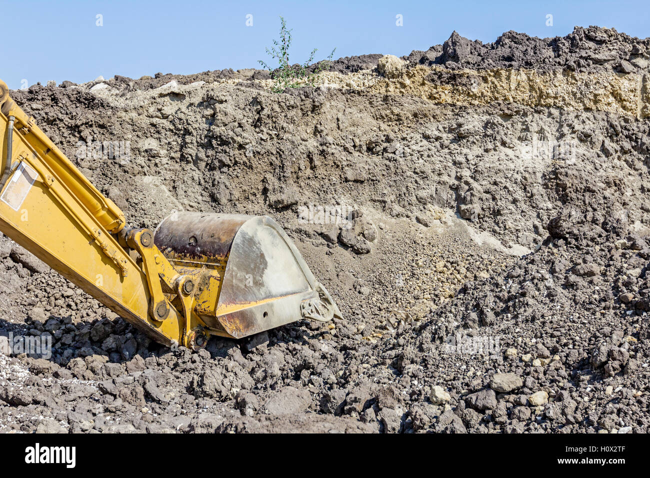 Yellow excavator is digging soil by pulling ground at construction site ...