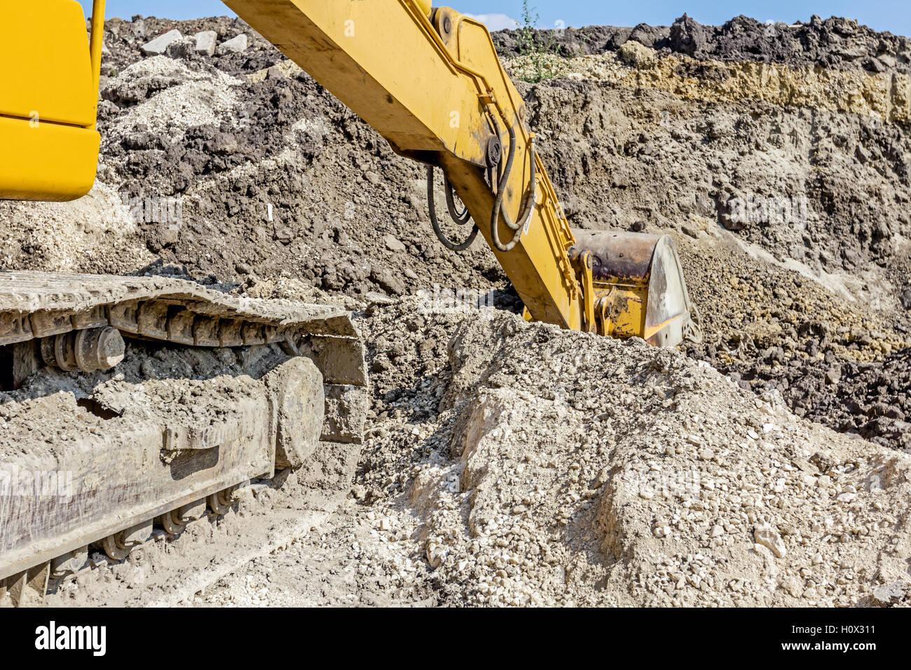 Yellow excavator is digging soil by pulling ground at construction site ...