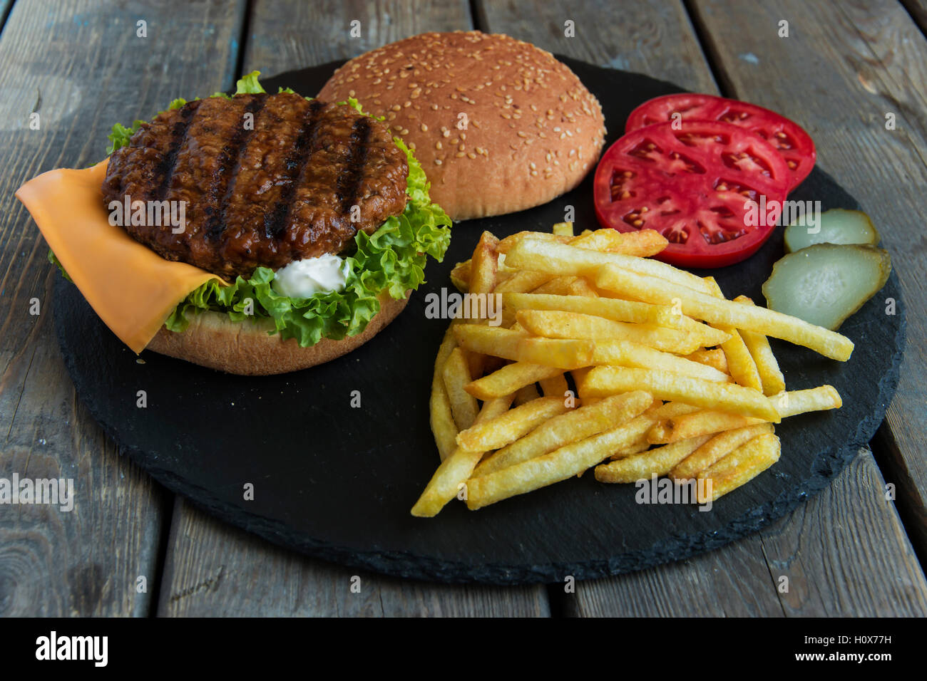 Beef hamburger grill french fries pickled cucumber tomato cheese Stock Photo