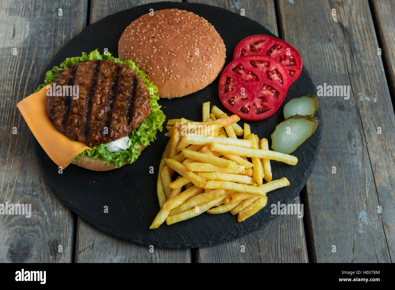 Beef hamburger grill french fries pickled cucumber tomato cheese Stock Photo