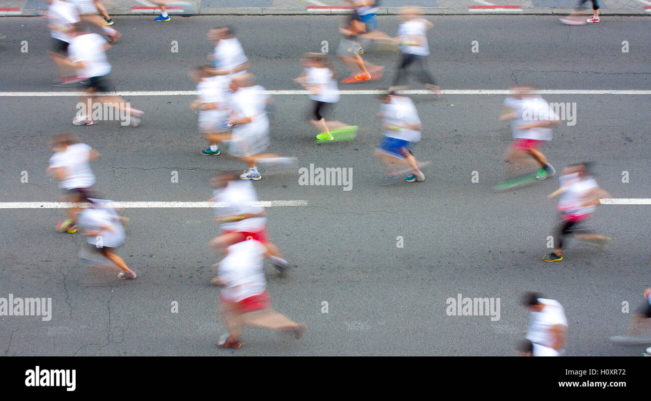 People in white T-shirts running semi marathon on city streets in attentional motion blur Stock Photo