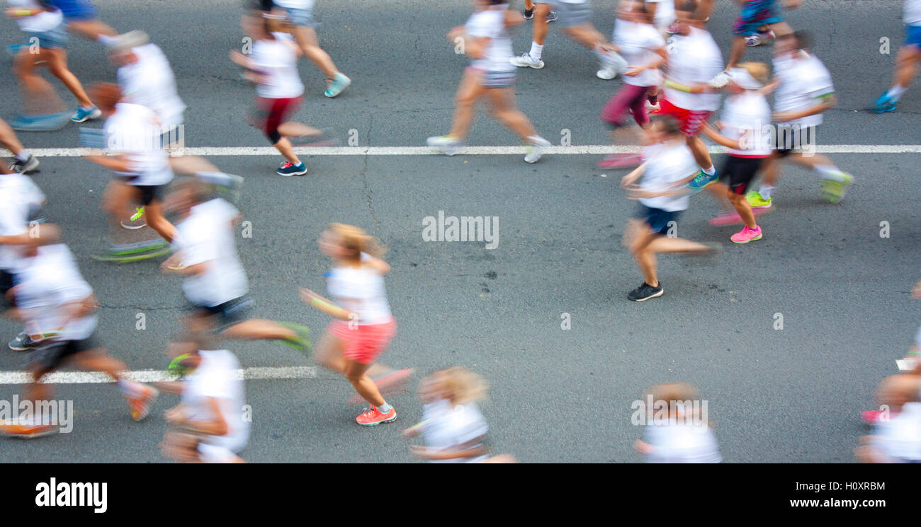 People in white T-shirts running semi marathon on city streets in attentional motion blur Stock Photo