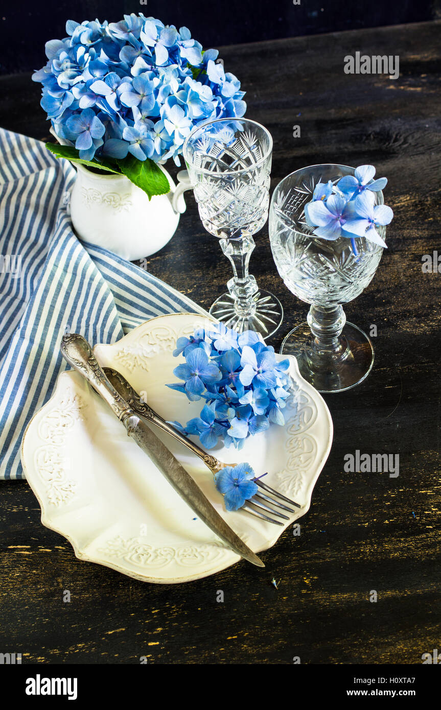 Vintage style table setting with fresh blue hydrangea flowers on rustic