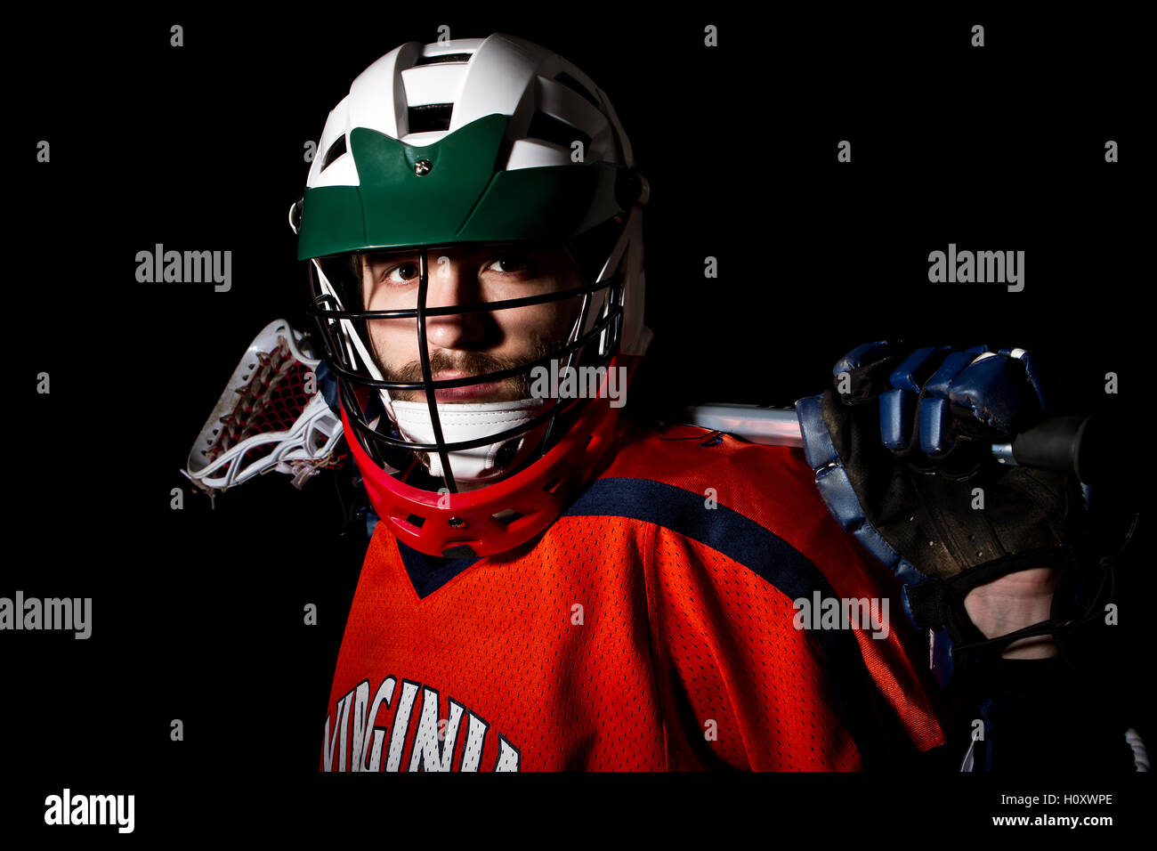 Lacrosse player wearing helmet and holding stick. Studio shoot on the