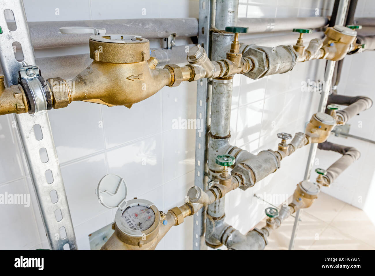 Water meters and valves in measuring place, tiled room with white tiles