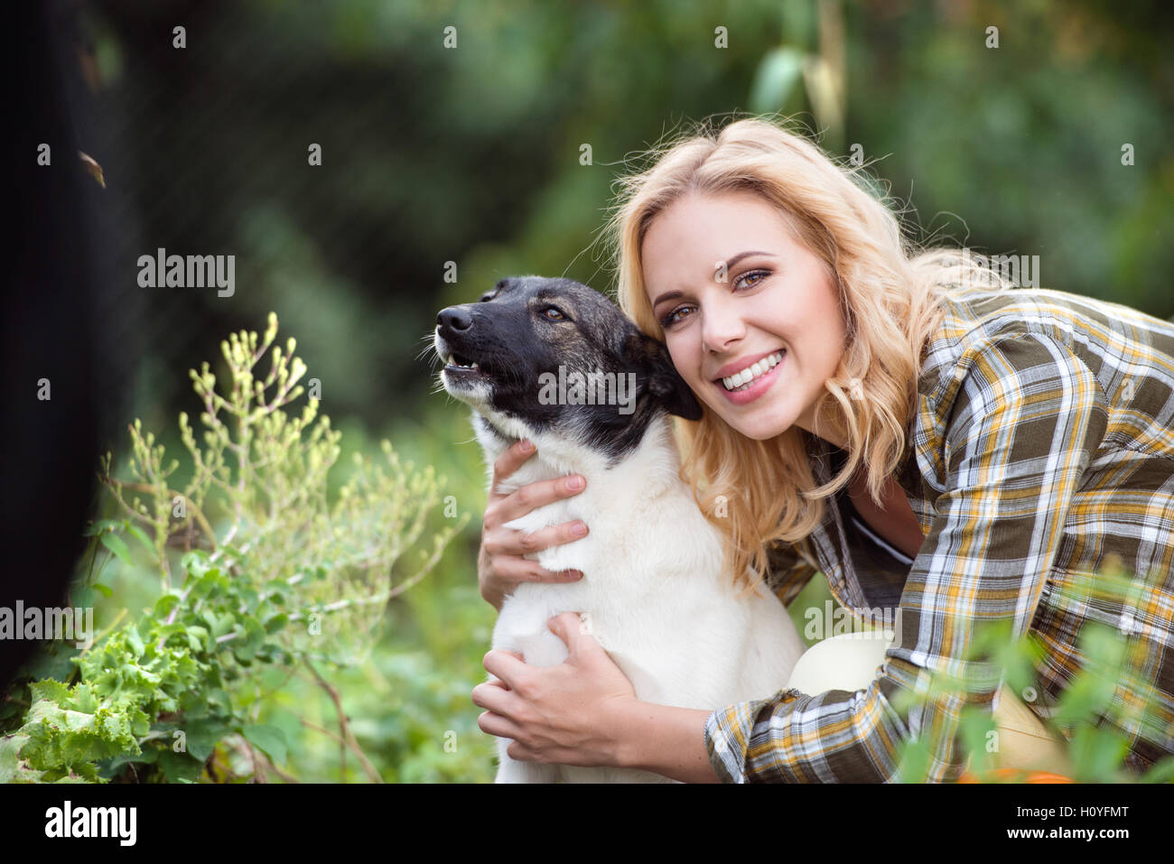 Beautiful blond woman with dog in green garden Stock Photo - Alamy