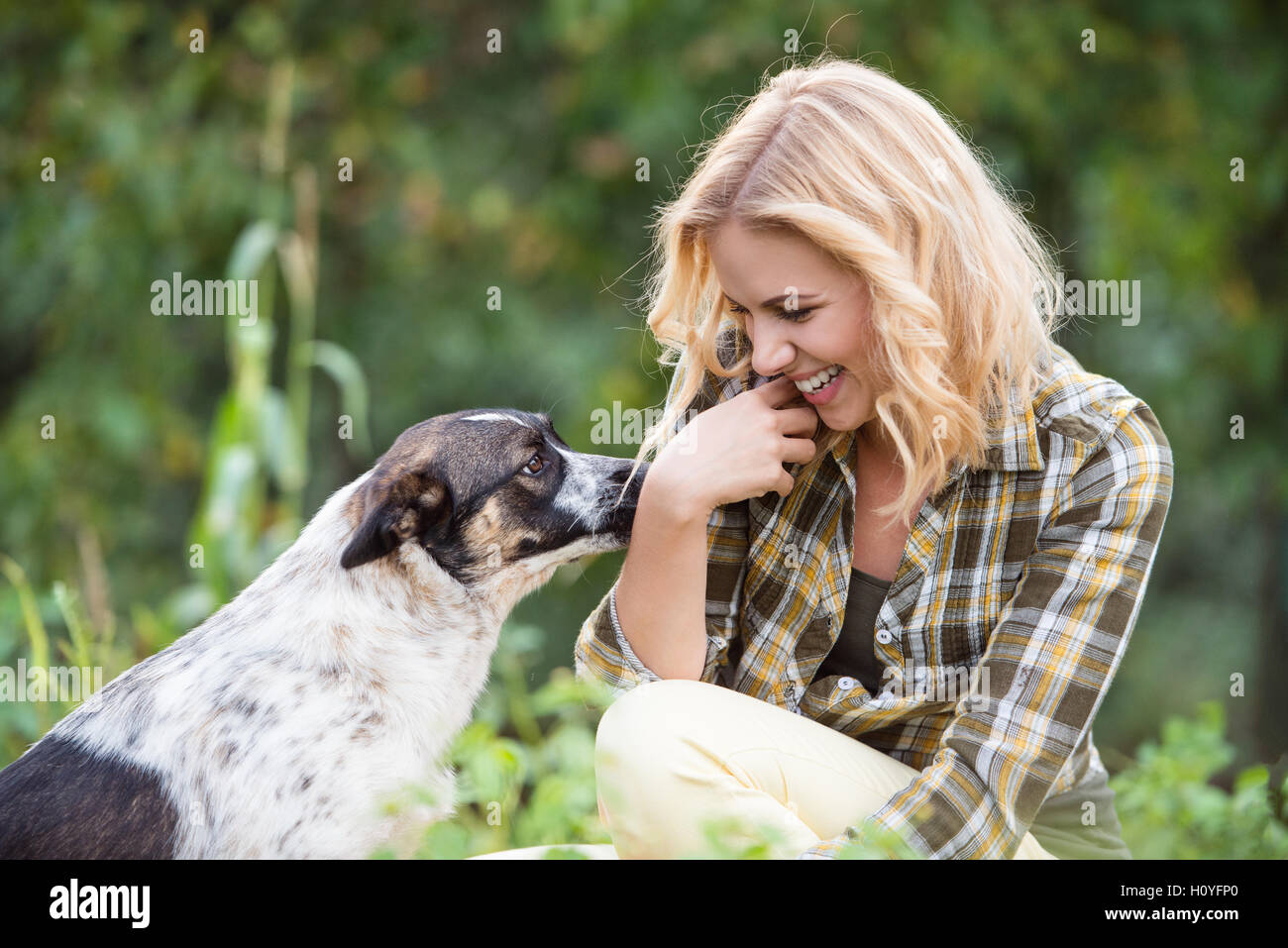 Beautiful blond woman with dog in green garden Stock Photo - Alamy