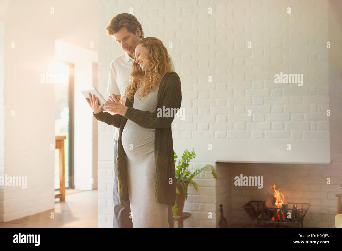 pregnancy couple digital tablet fireplace Stock Photo Alamy