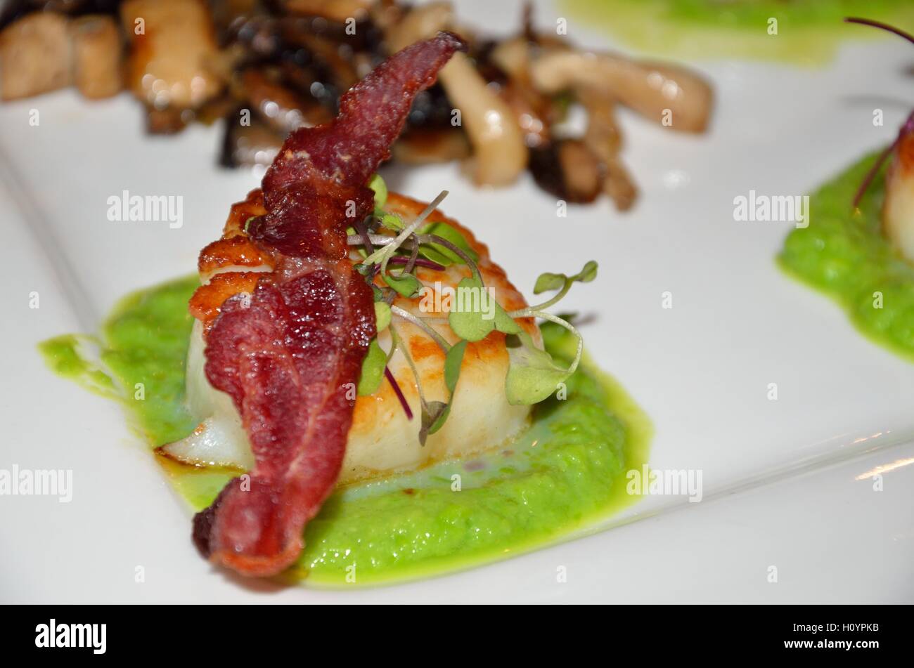 Scallop topped with bacon in a pea puree with mushrooms Stock Photo Alamy