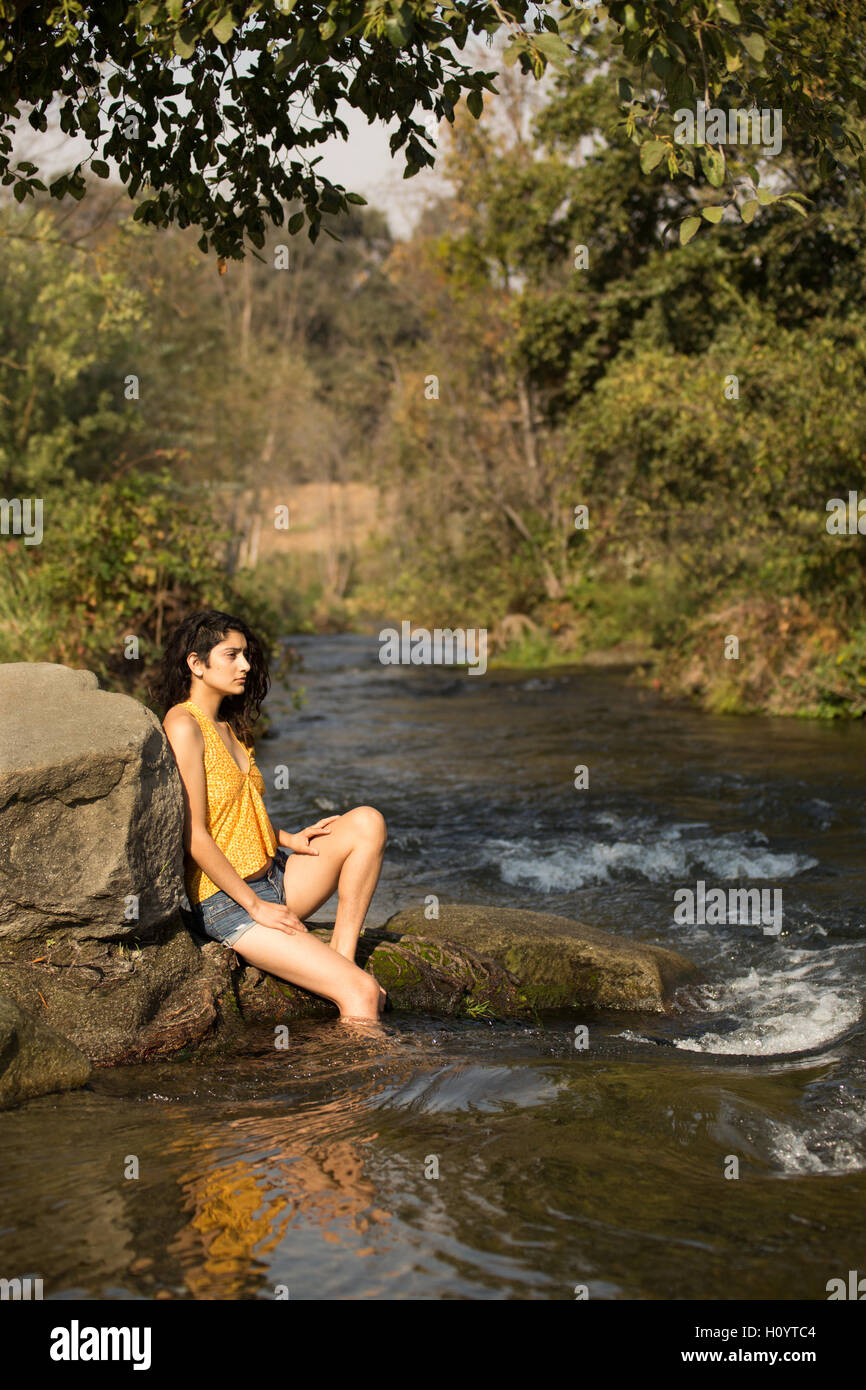 A beautiful young organic lifestyle woman in a river with natural hair dreadlocks in handmade clothing Stock Photo