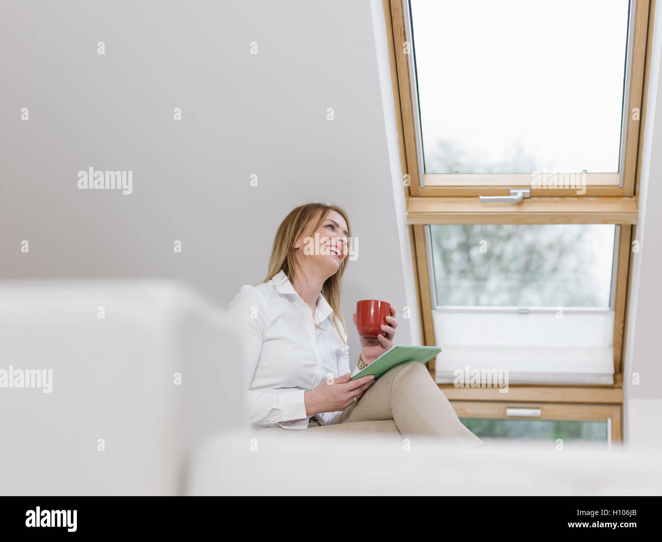 Relaxed young woman sitting on sofa with tablet Stock Photo - Alamy