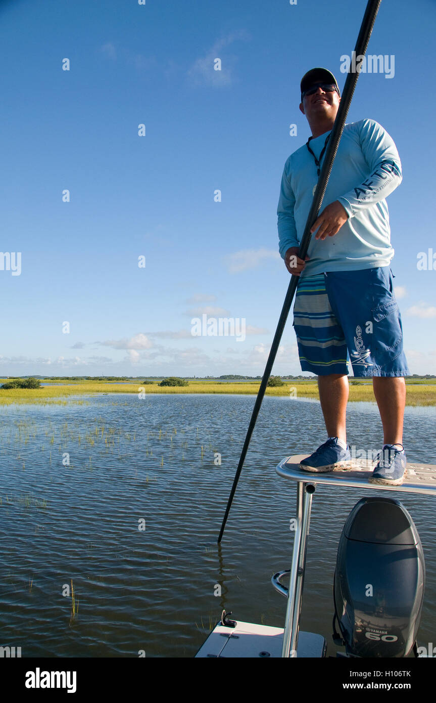 An inshore charter guide poles the flats on Florida's pristine Intercoastal waterway searching for signs of redfish. Stock Photo