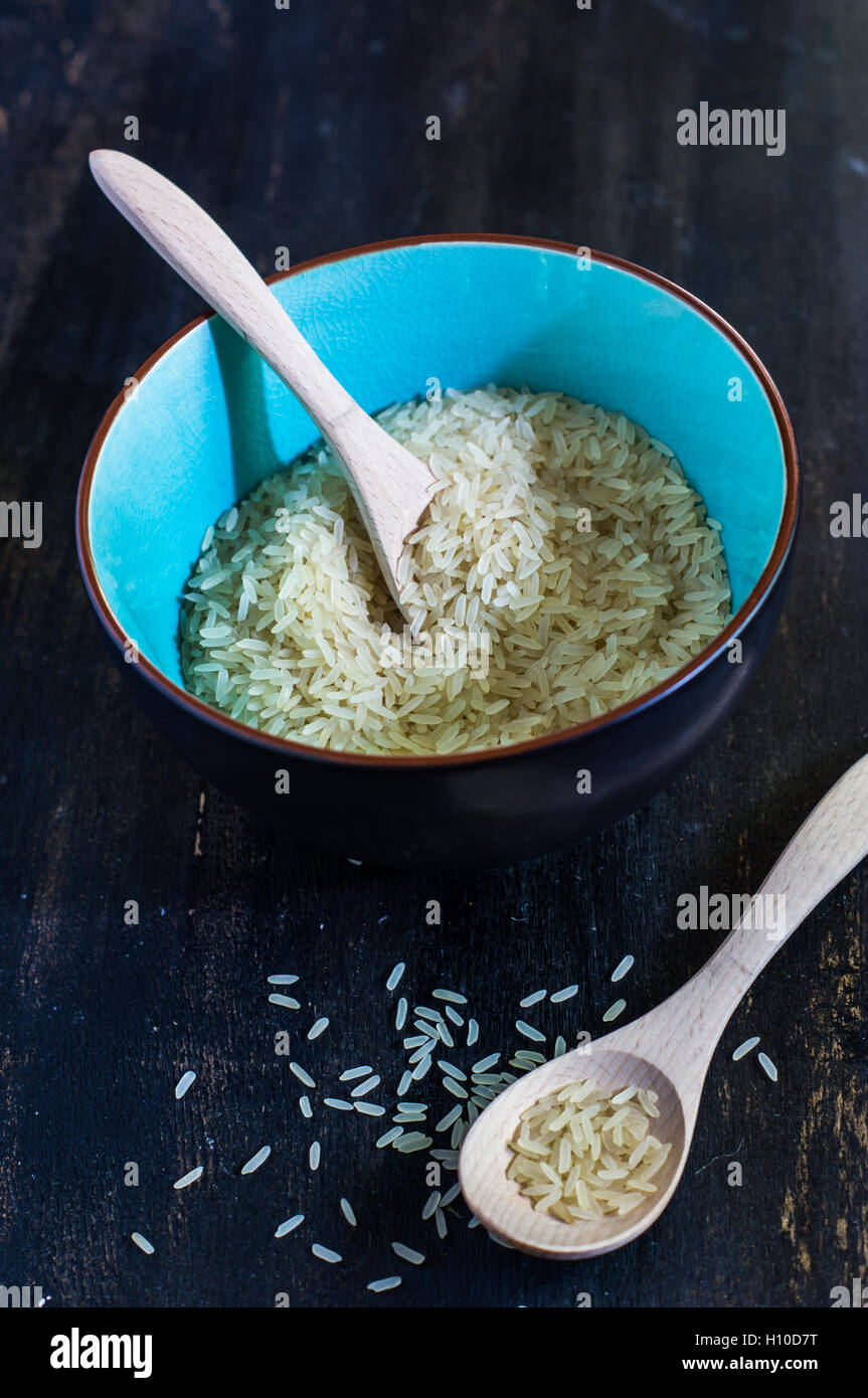 Vintage blue bowls with uncooked rice on dark wooden table Stock Photo