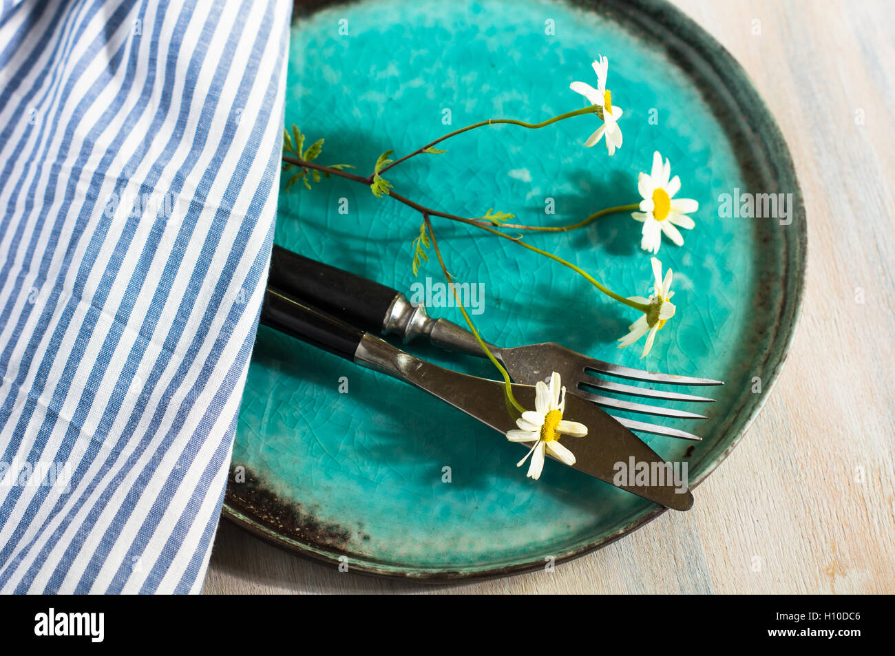 Rustic table setting with vintage silverware and plates and wild daisy ...