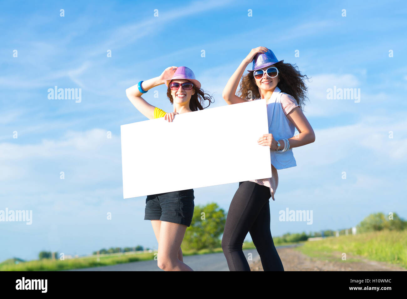 Two young women stand with a blank banner Stock Photo - Alamy