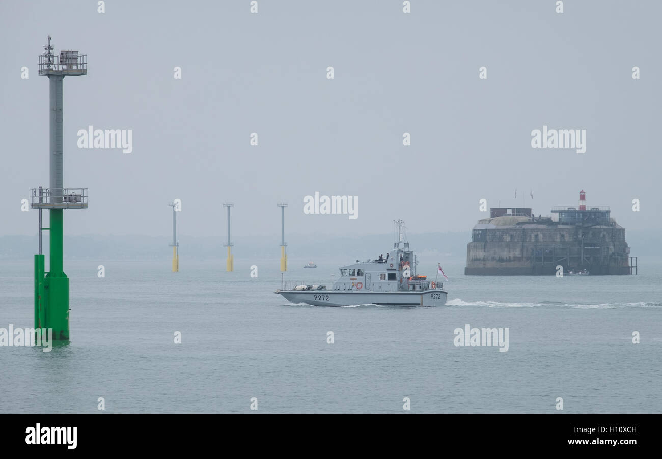 HMS Smiter (P272) sails out of Portsmouth Harbour past the navigation light piles that have been installed in the Solent. Stock Photo