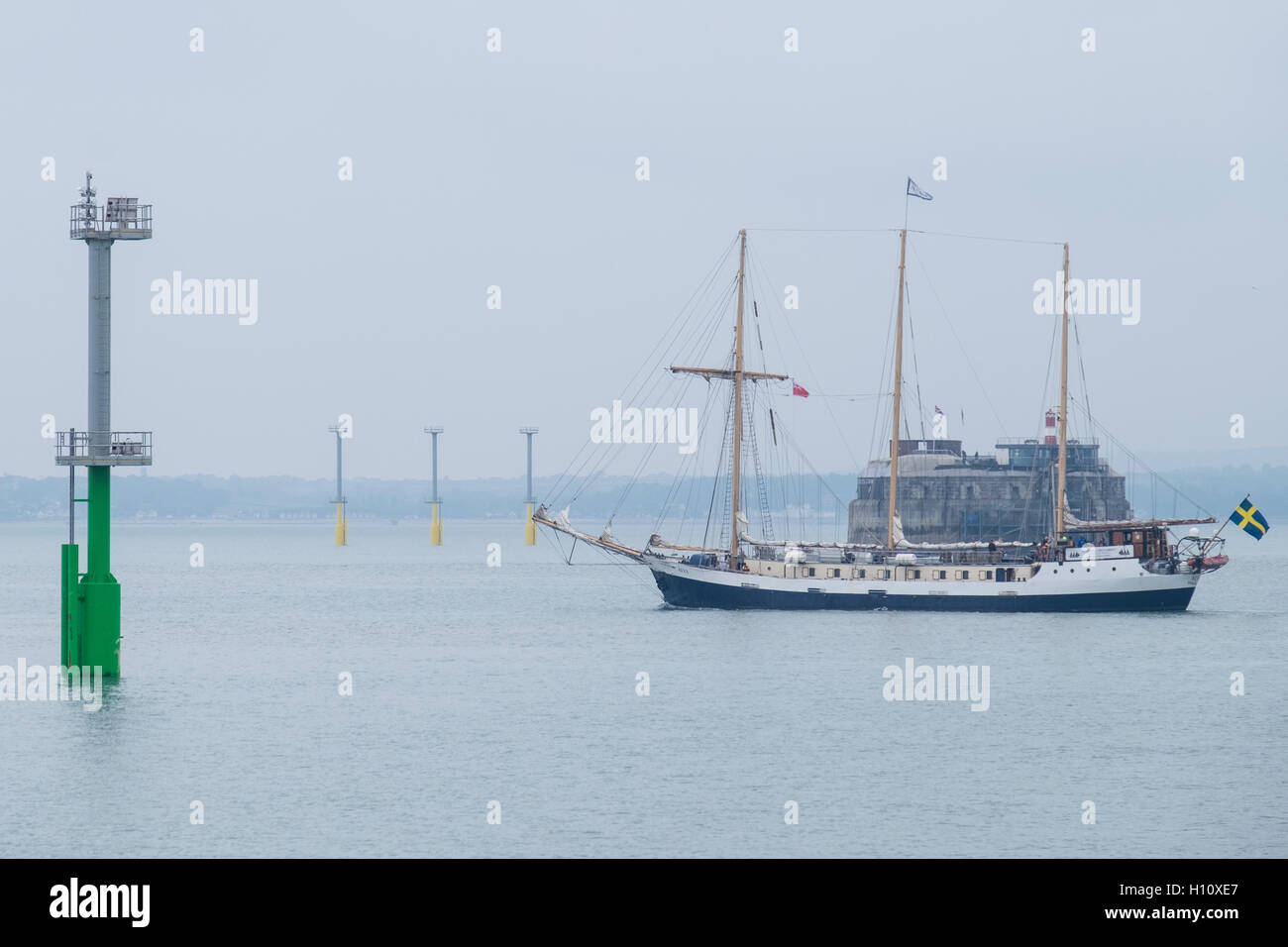 Swedish training ship, 'Alva', sails out of Portsmouth Harbour past the navigation light piles that have been installed in the Solent. Stock Photo