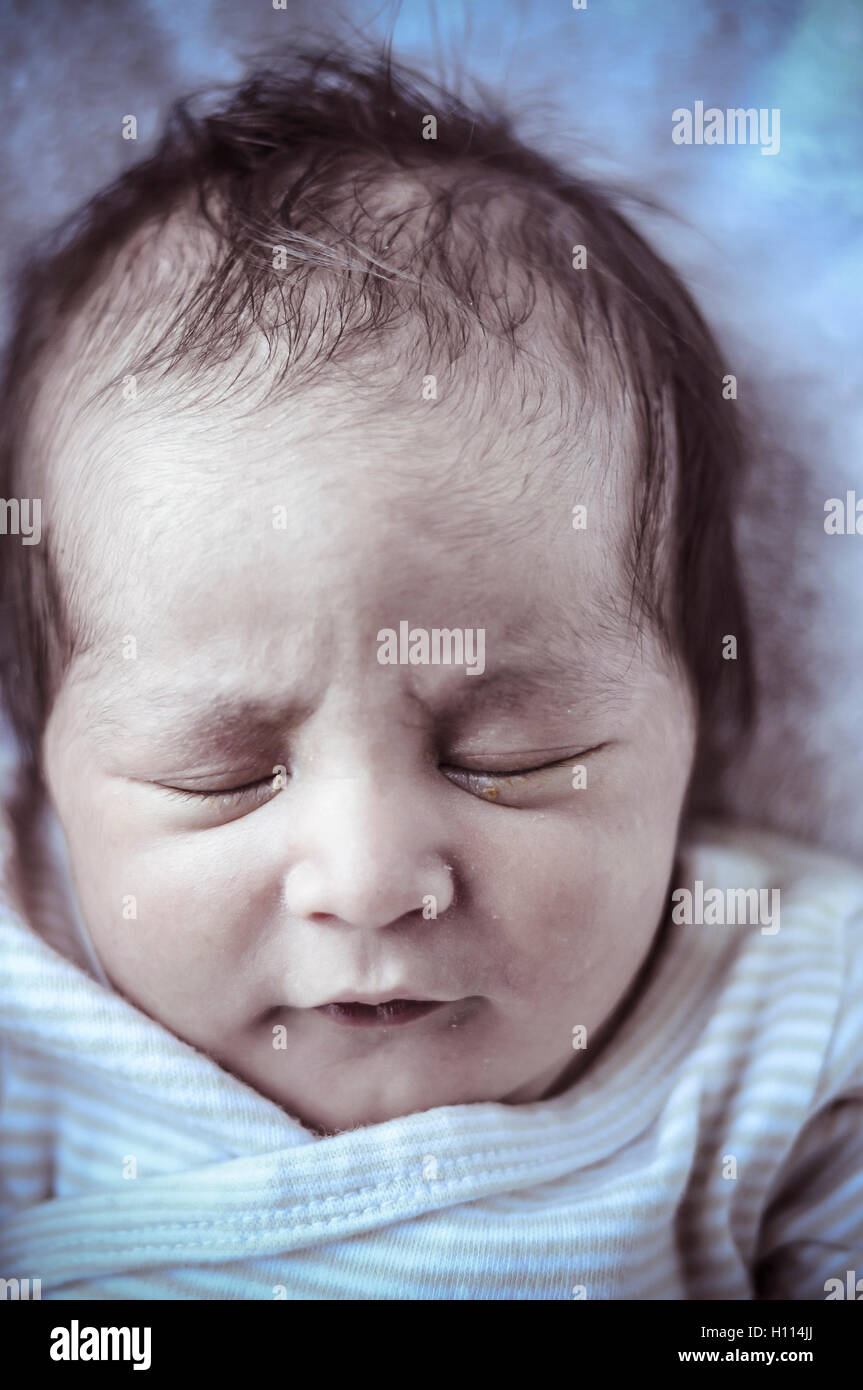 new born baby curled up sleeping on a blanket, multiple expressi Stock