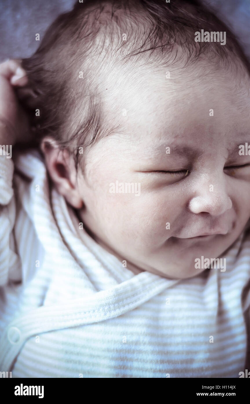 new born baby curled up sleeping on a blanket, multiple expressi Stock