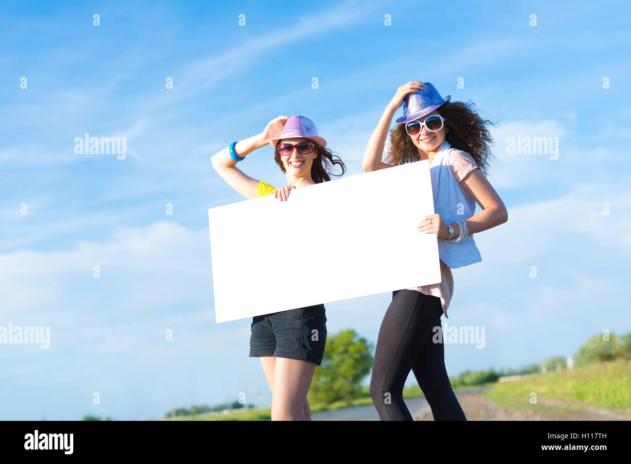 Two young women stand with a blank banner Stock Photo - Alamy