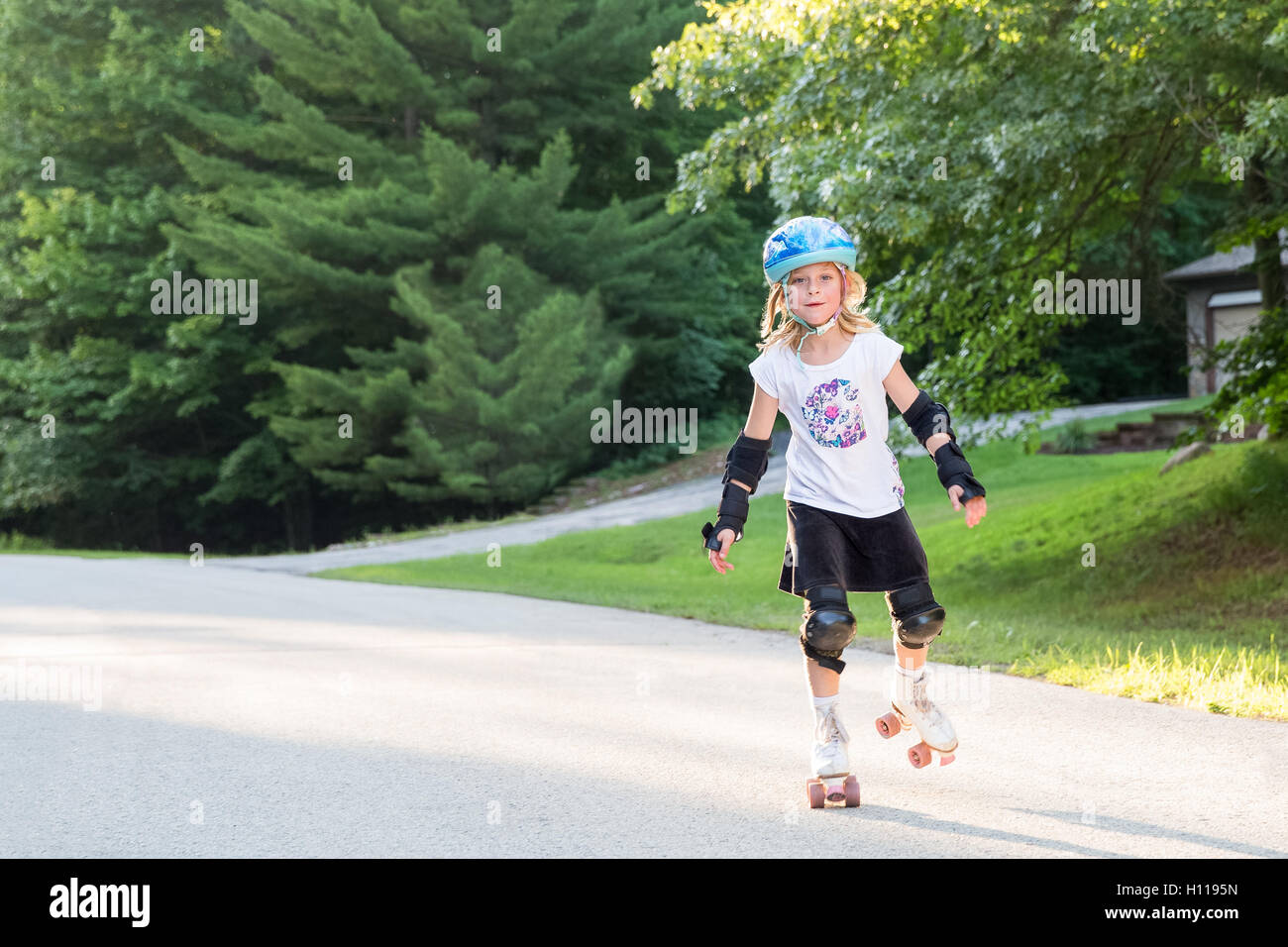 Happy, young girl on roller skates wearing safety gear, skating toward