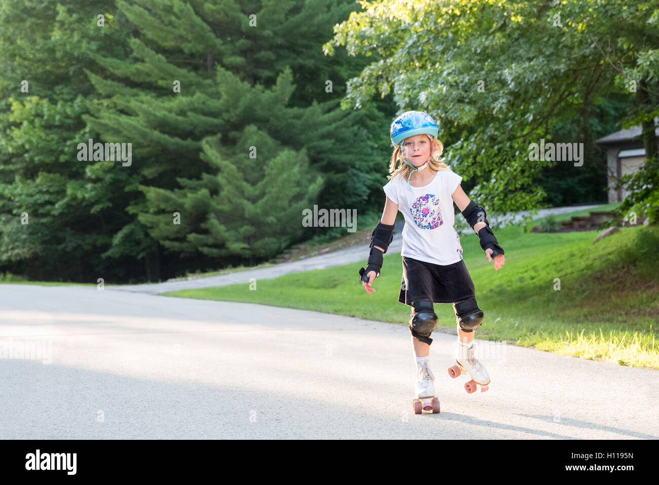 Happy, young girl on roller skates wearing safety gear, skating toward  viewer, smiling, and looking into camera. Copy space Stock Photo - Alamy