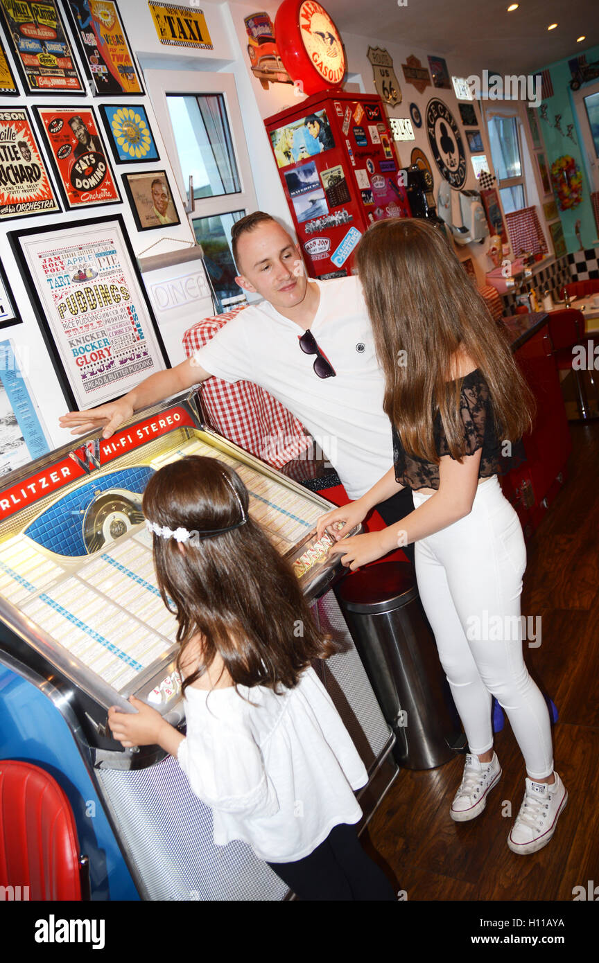 Siblings in a 1950's diner stood next to a Wurlitzer jukebox Stock Photo