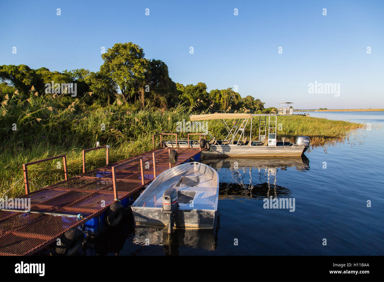 An aluminium hulled fishing boat moored on a jetty overlooking the scenic Chobe River in Kasane Stock Photo